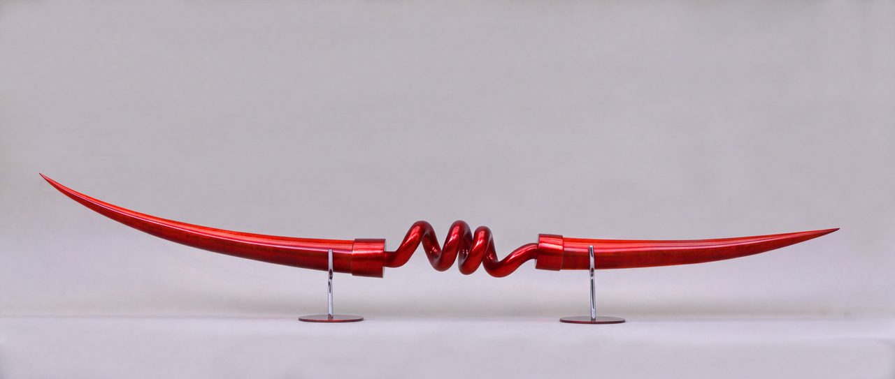 Bardiche III, a long curved red horn form joined at its centre by a coiled red spring section, by David Hamilton