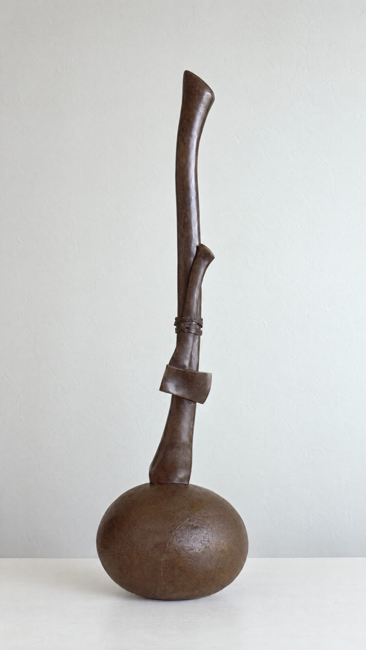A Walk in the Woods, a dark bronze forked branch form rising from a smooth rounded stone base, by David Hamilton