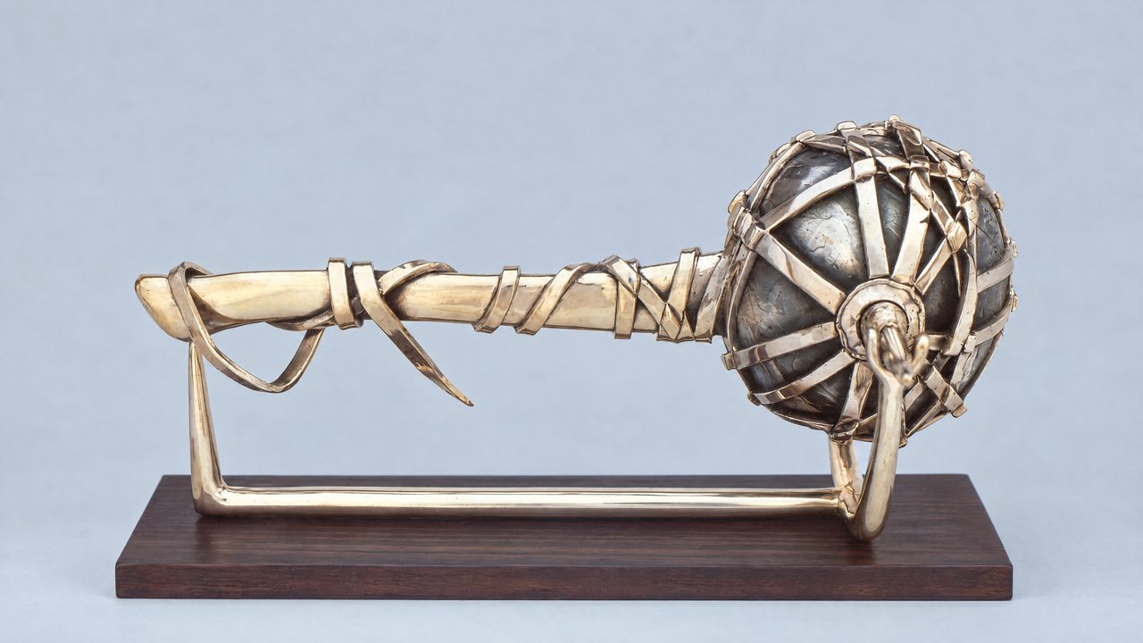 Fortunes Wheel, a bronze axe head bound in a woven cage and hung by cords from a curved handle, by David Hamilton