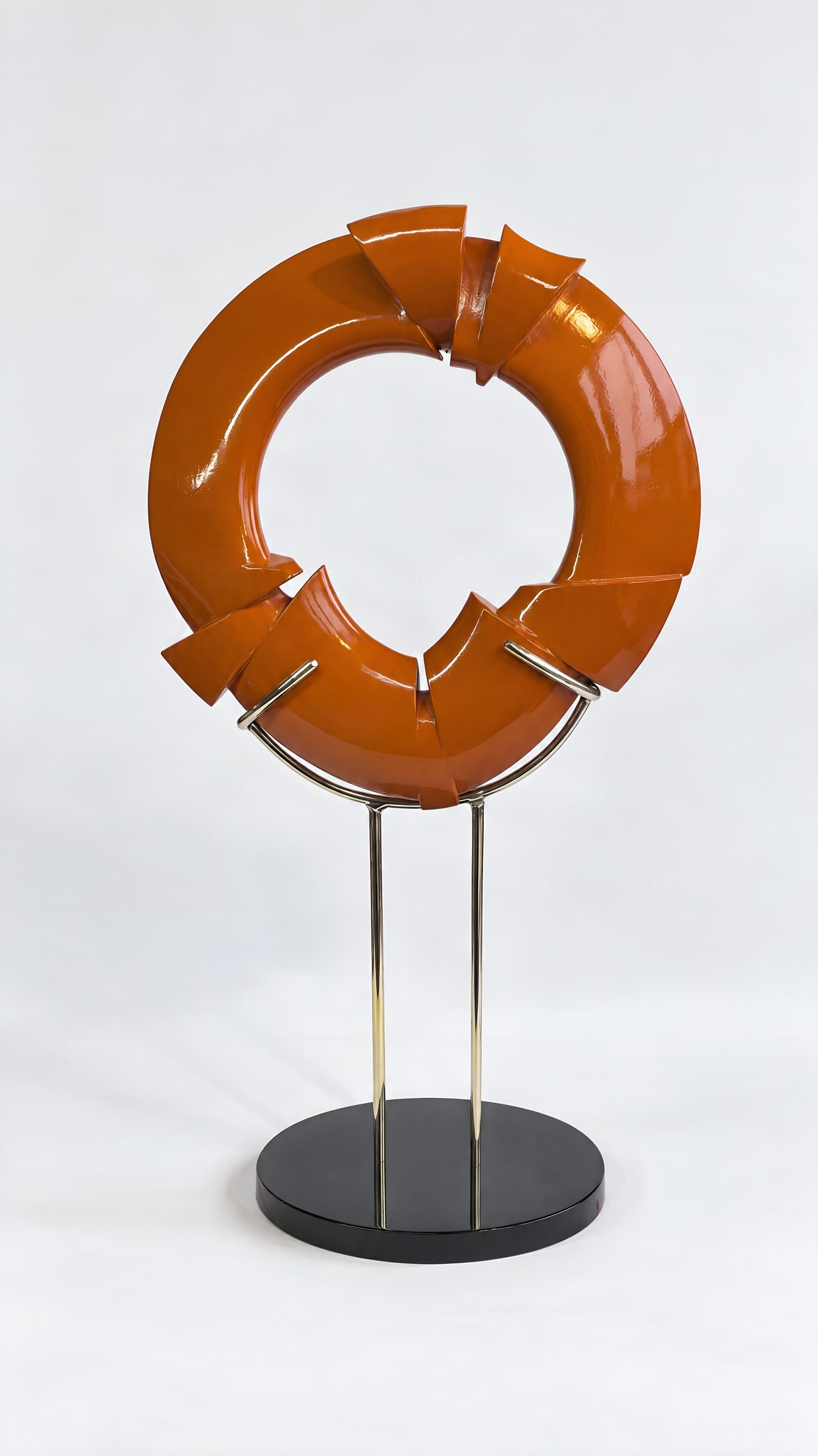 A broken-ring sculpture in glossy burnt-orange lacquer with a twisted knot at its base, mounted on a stand, by David Hamilton