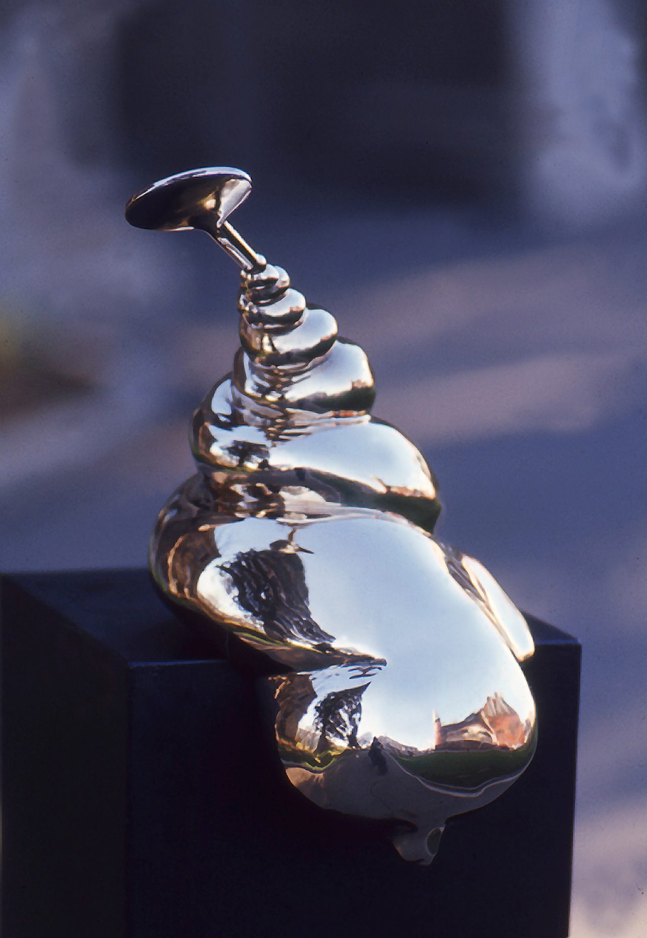 Twist, a polished bronze form spiralling upward from a rounded base to a small round disc handle, by David Hamilton