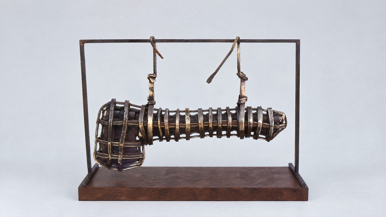 Safe Bequest, a bronze axe head enclosed in a rectangular cage frame with hanging cords, by David Hamilton