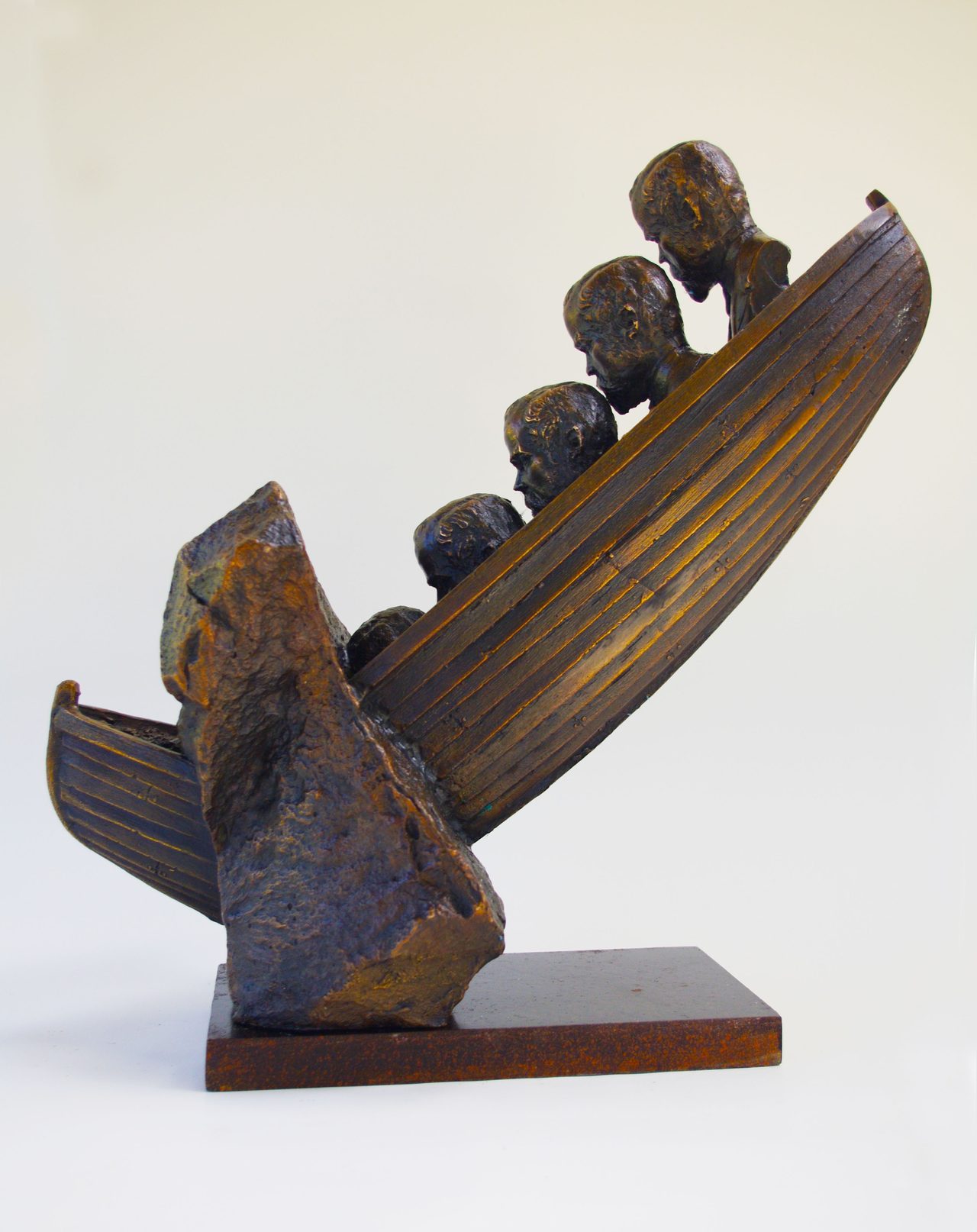 Five Folios, a bronze boat tipped on a rock outcrop, its bow lined with small carved heads looking down its hull, by David Hamilton
