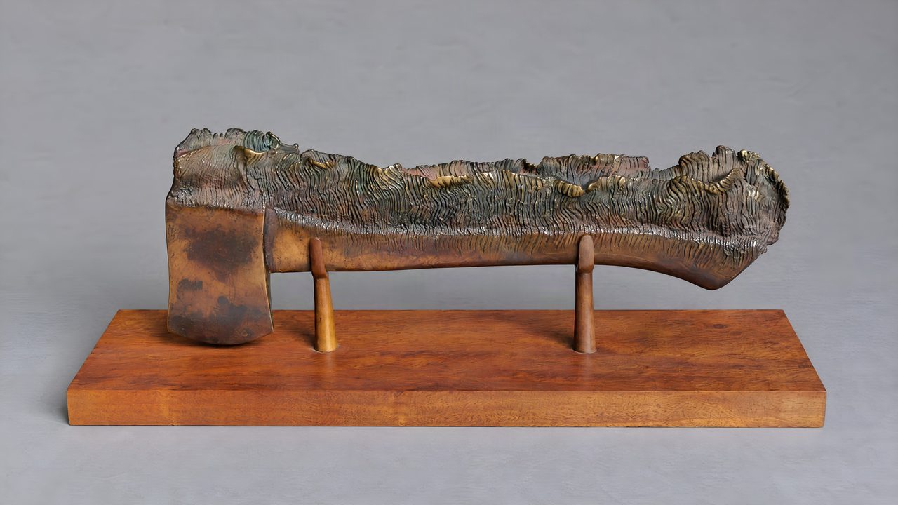 Ridgetop, a bronze axe with a fringe of thin dark branches along its blade edge, raised on two stands, by David Hamilton