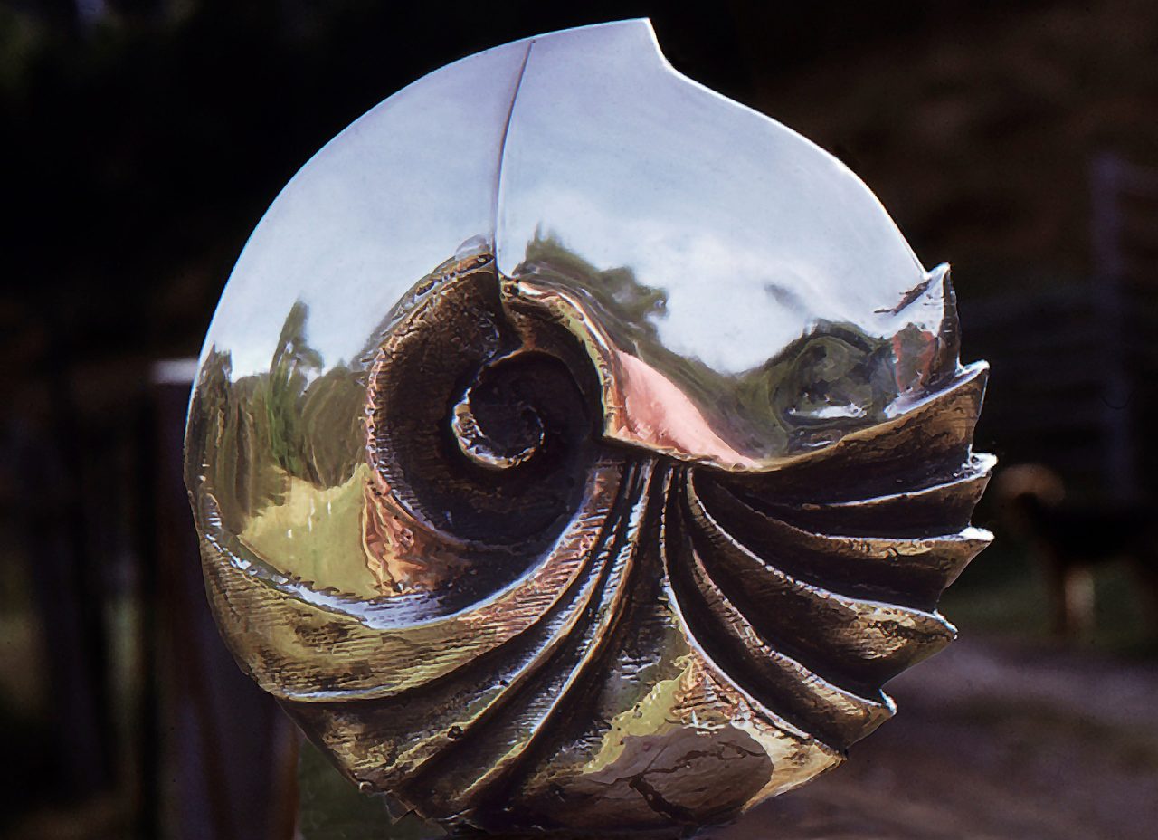 Nautilus, a polished bronze vessel coiled into a spiral nautilus shell shape, by David Hamilton