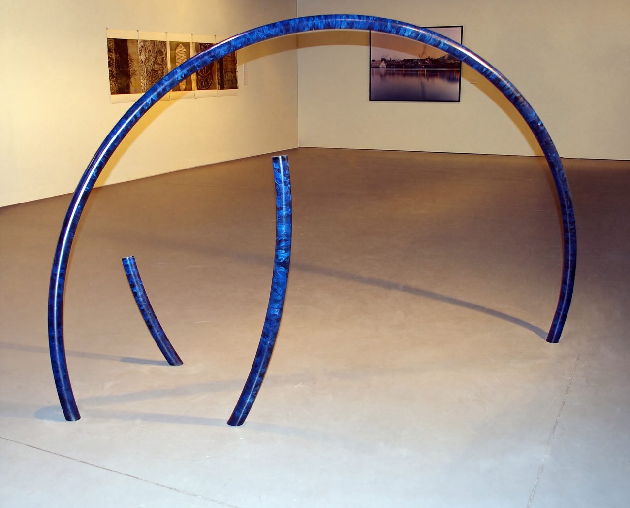 In Blue, a large blue mottled painted steel ring standing on two upright rods in a gallery, by David Hamilton