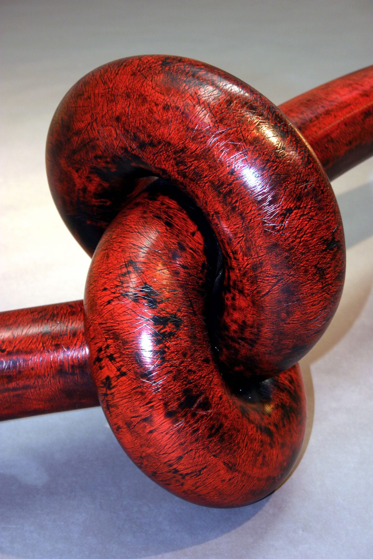 Knot, a close view of the tightly tied red-and-black painted steel knot, by David Hamilton