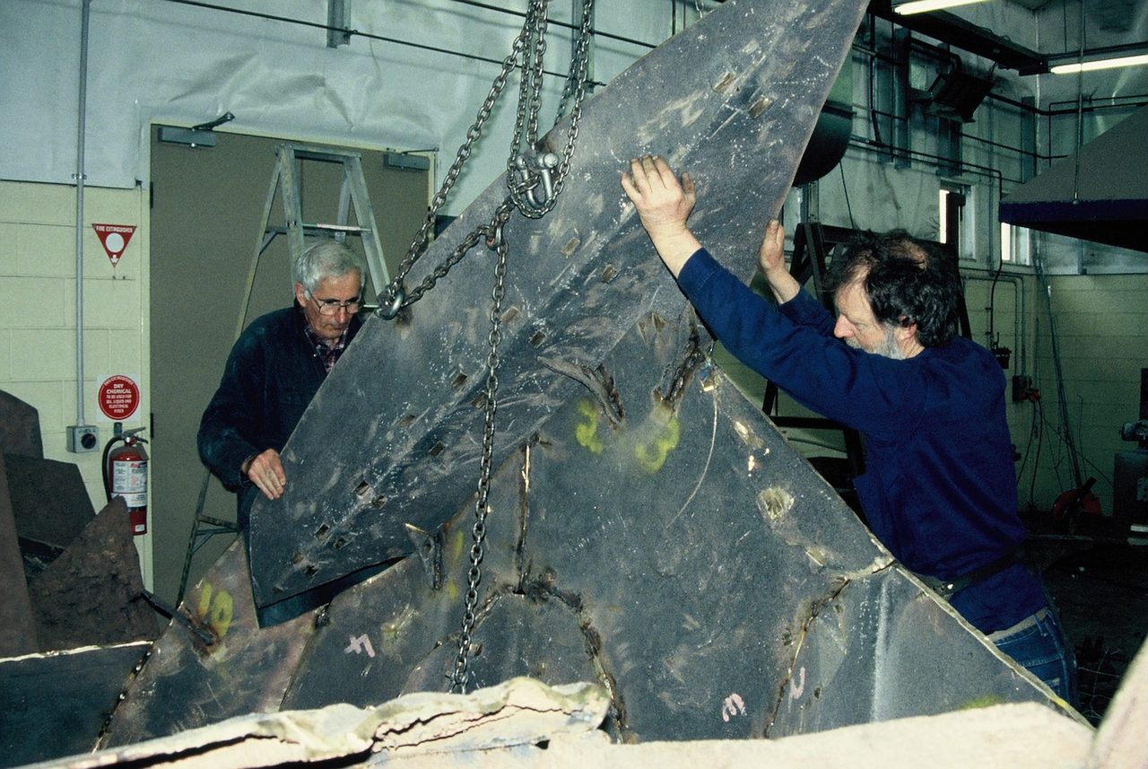 David Hamilton and a colleague guiding a cast bronze section of Overcoming Adversities on chains in the foundry