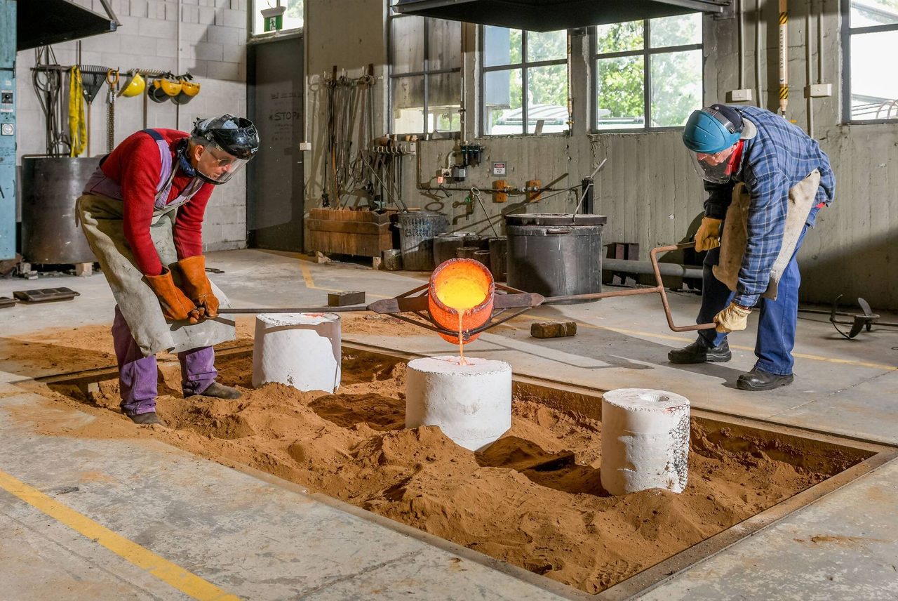 Using a pouring shank, Hamilton and Boldkald pour the molten bronze into the moulds holding wax-covered cardboard figurines.