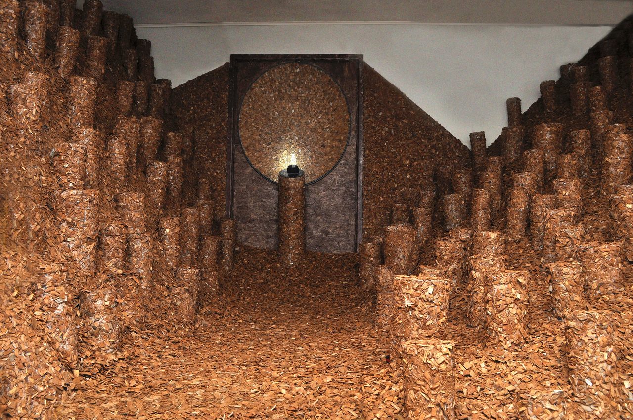 Memorychip, a gallery corridor entirely lined with stacked woodchip-textured columns leading to a lit oval niche, by David Hamilton
