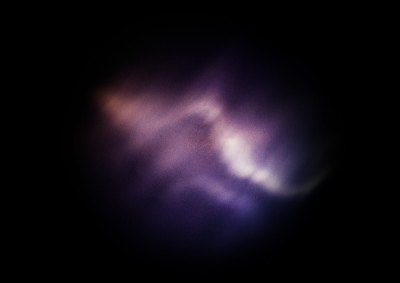 Untitled, an abstract long-exposure photographic study showing a soft cream and pink glow against black, by David Hamilton