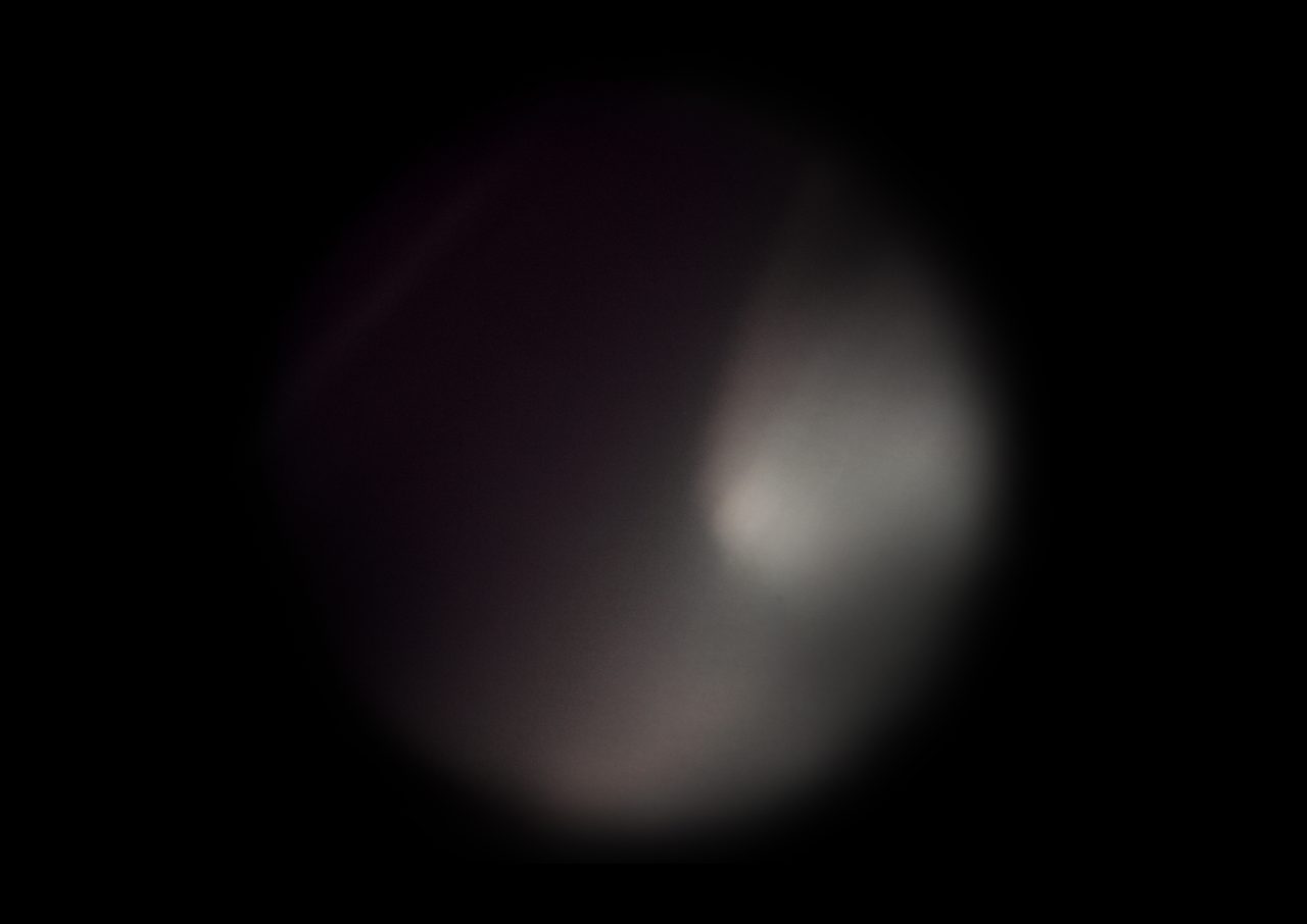 Untitled, an abstract long-exposure photographic study showing a pale rounded glow shading from dark maroon to white against black, by David Hamilton