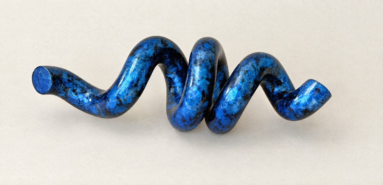 Fragment, a mottled blue and black painted steel tube coiled into a loose spiral, lying on its side, by David Hamilton