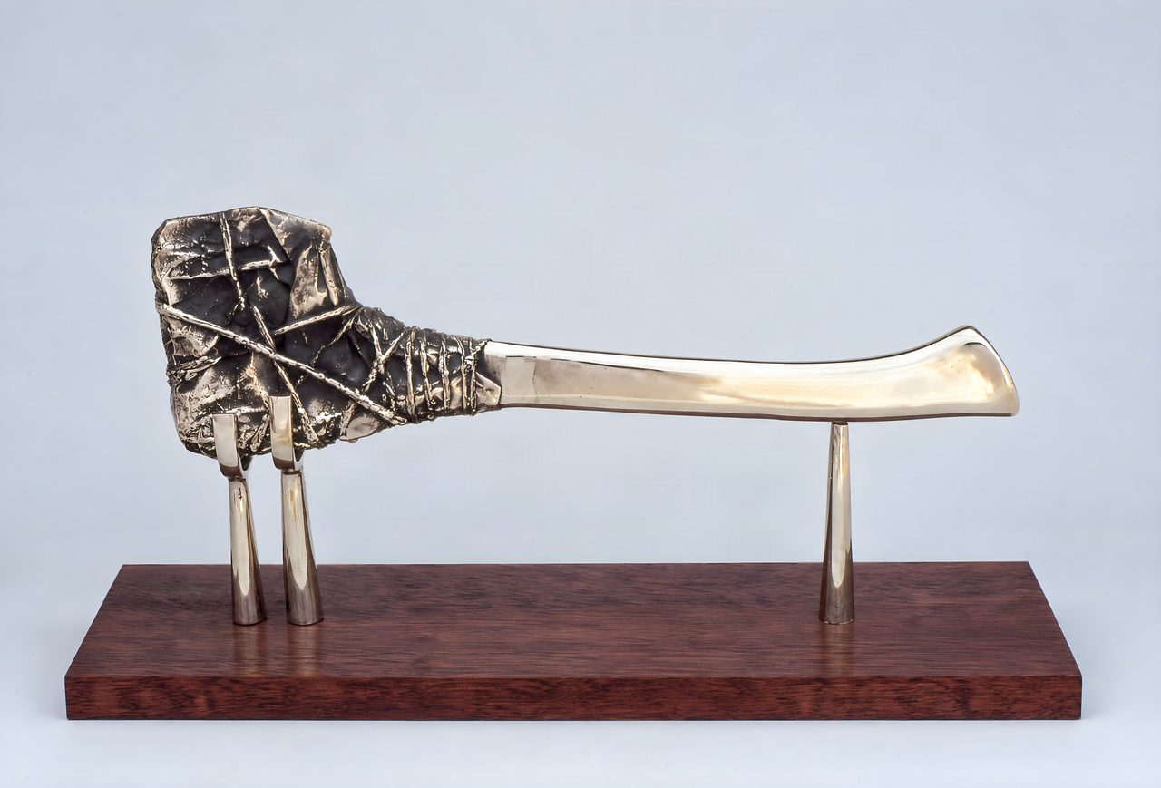 Wrapped Axe, a bronze axe head bound with wrapped straps set on a polished curved blade, raised on two stands, by David Hamilton