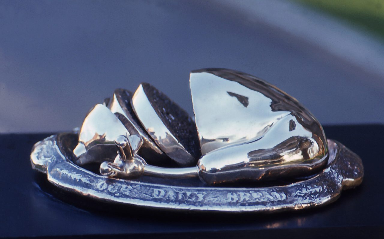For give us this day our daily bread, a polished bronze form of sliced loaves on an oval plate reading OUR DAILY BREAD, by David Hamilton