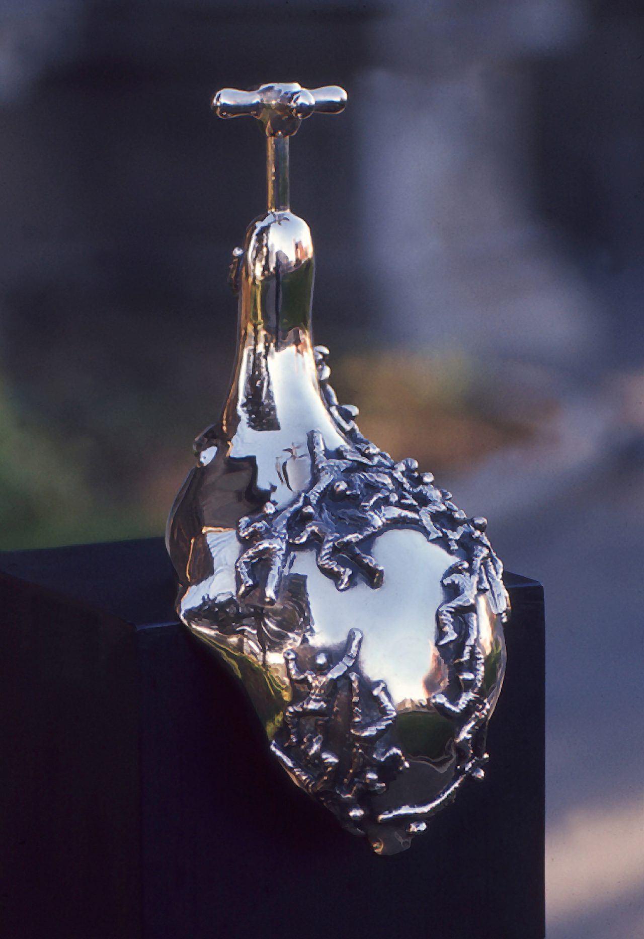 People, a polished bronze teardrop form crowded with tiny embossed figures clustered along one side, by David Hamilton