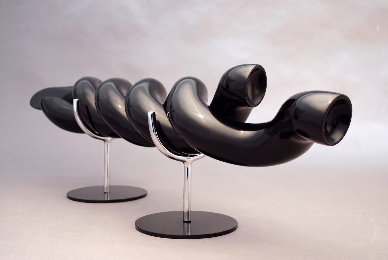 Torque, a coiled black painted steel rod with open trumpet-like ends, raised on two thin stands, by David Hamilton