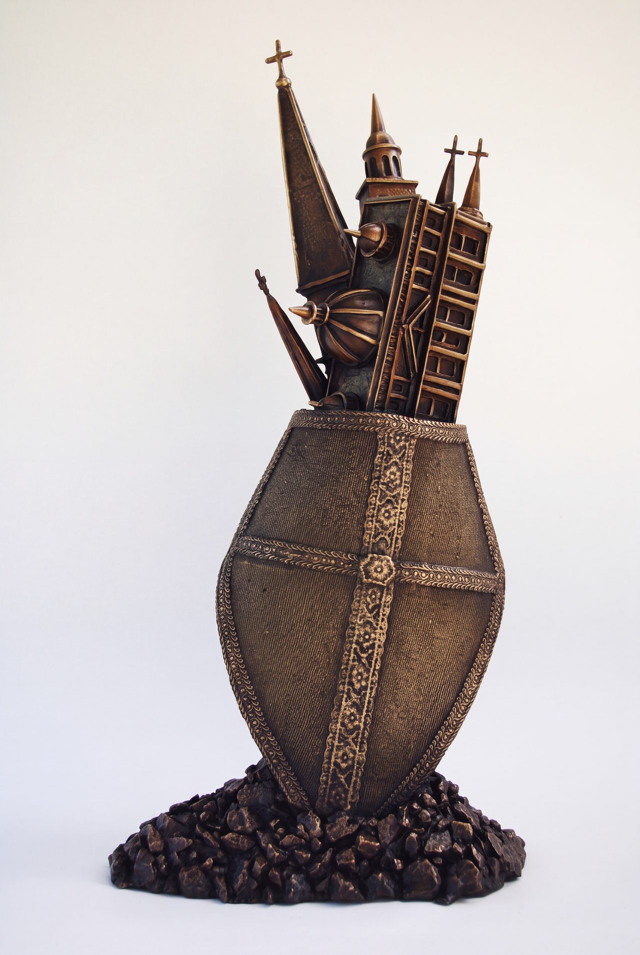 Bishops Hat, a bronze sculpture of church spires and towers rising from a cross-banded shield on a rocky base, by David Hamilton
