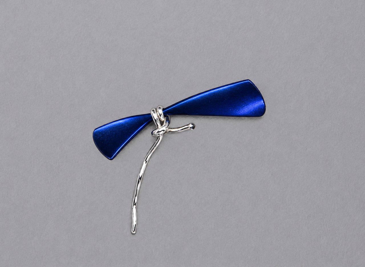 A dark curved pendant with a silver wire loop and a long trailing tail, by David Hamilton